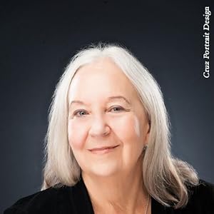 Portrait of a smiling woman with long silver hair against a dark background.