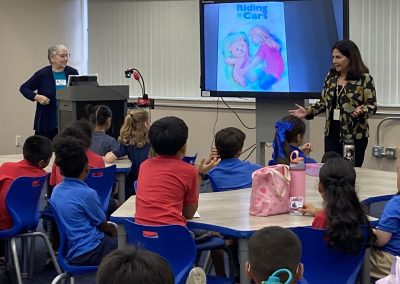 Two women lead a classroom discussion about the children’s book Riding in Cars as elementary students listen from their seats.